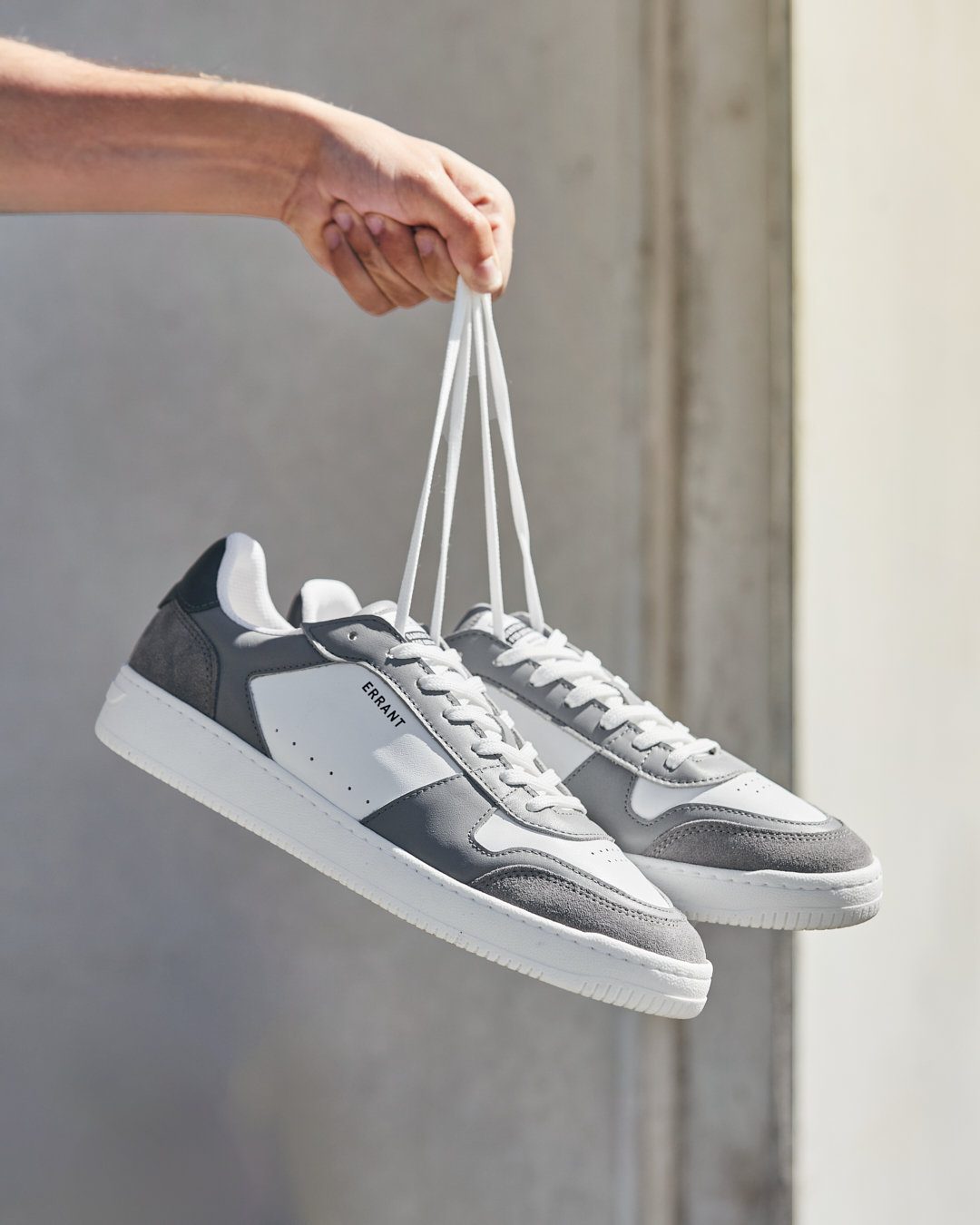 Grå sneakers holdt i snørebåndene